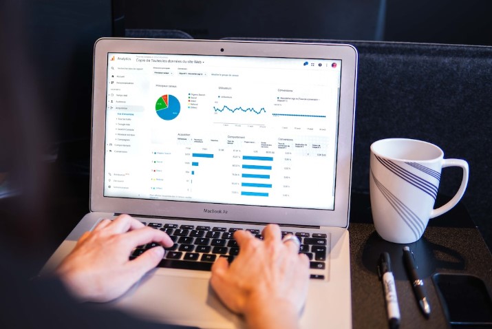 An employee types on a laptop at their desk while looking at several data visualizations.